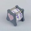 The NC-2 number counter viewed from an isometric angle showing the top dials and side 1 heart. The version shown has a dark gray base and a pink heart in the middle on both sides 1 and 2.